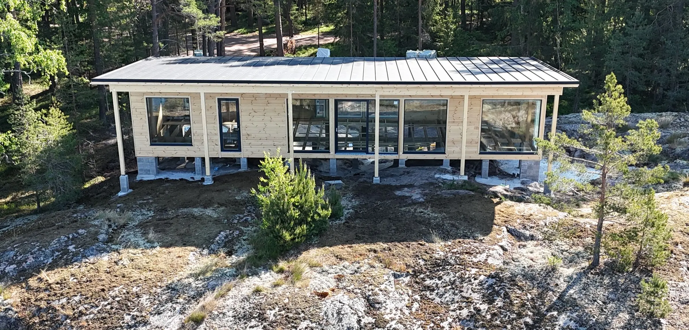 Uusi puurakenteinen vapaa-ajan asunto kallioisella metsätontilla