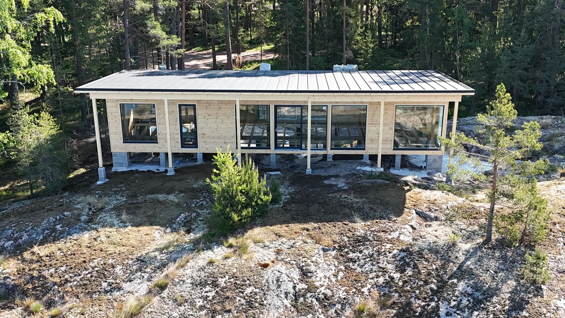Uusi puurakenteinen vapaa-ajan asunto kallioisella metsätontilla
