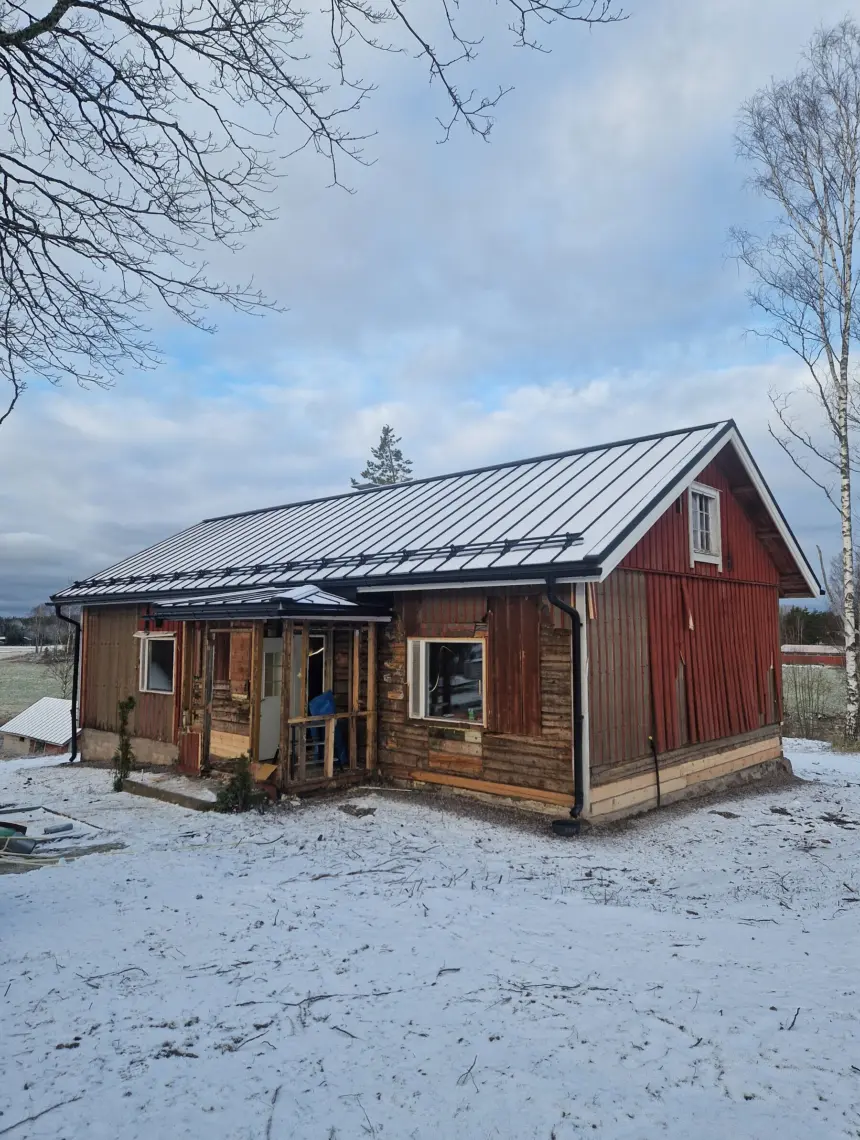 Saneerattava punainen hirsitalo talvella