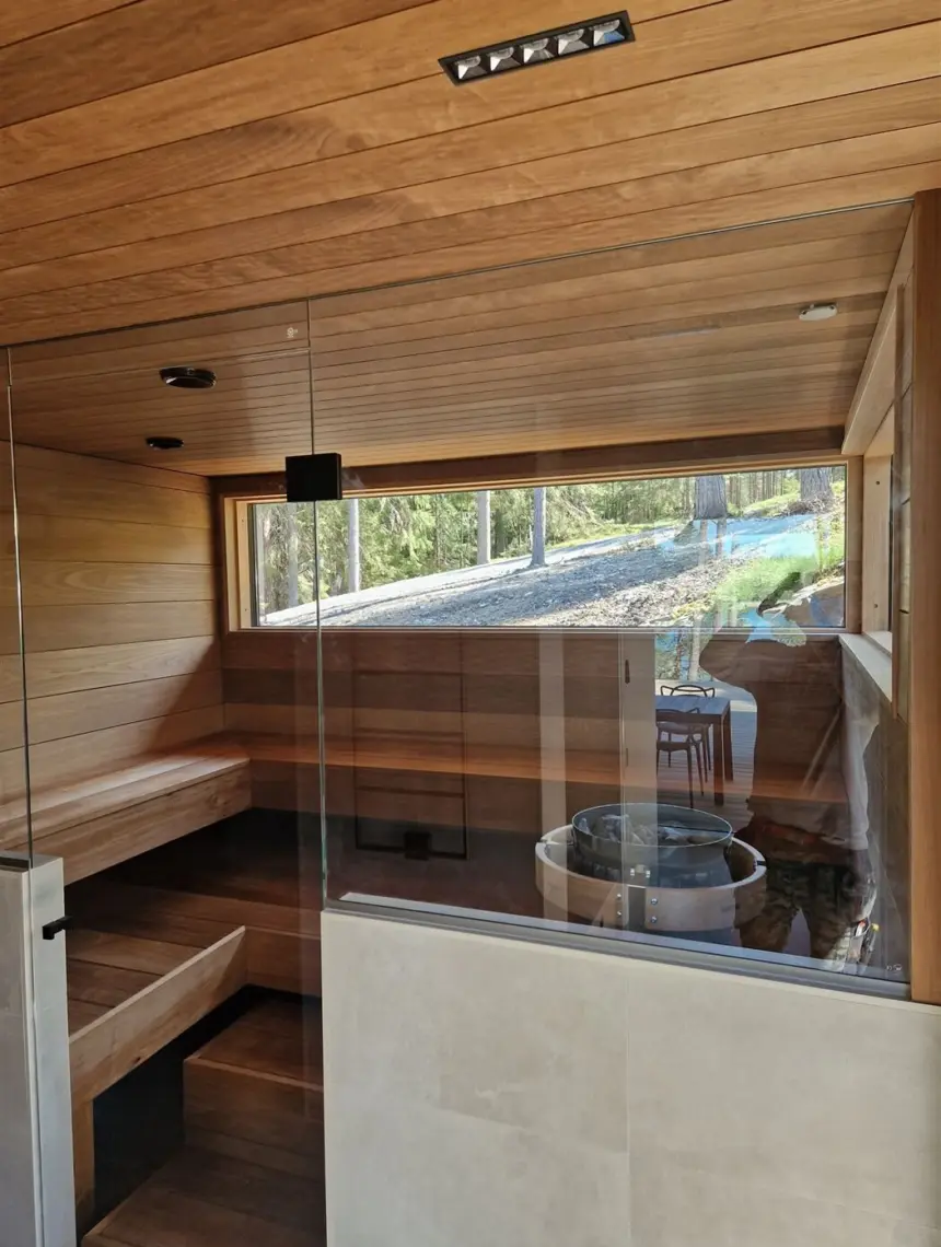 Sauna, jossa lasiseinä ja leveä ikkuna metsään
